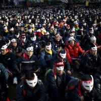 Protesters wearing masks take part in an anti-government rally in central Seoul on Saturday. | REUTERS