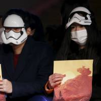 A fan wearing a face mask waits for a red-carpet event before the China premiere of the film \"Star Wars: The Force Awakens\" amid heavy smog in Shanghai on Sunday. | REUTERS