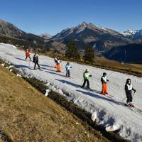 Children from ski schools practice on a thin layer of snow toward the resort of Leysin, Swiss Alps, on Monday. In a season traditionally associated with ice-skating, snowball fights and mulled wine in wintry Europe, birds are chirping, flowers blooming and fake snow covering Alpine ski slopes in one of the warmest Decembers on record. | AFP-JIJI