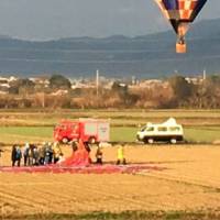 Firefighters gather around a crashed hot air balloon in a rice paddy in Kanzaki, Saga Prefecture, on Sunday. | KYODO