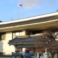 A policeman guards the South Korean Consulate General in Yokohama Saturday after a box containing dried feces was found in the parking lot outside the building. | KYODO