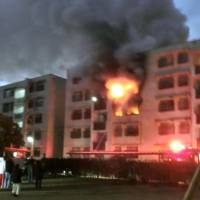 A photo provided by a neighbor shows a burning apartment building in Omuta, Fukuoka Prefecture, early Sunday morning. | KYODO