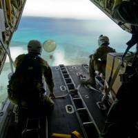 Cpl. Teome Matamua and Sgt. Phillip McIllvaney of the Australian Army 176th Air Dispatch Squadron loadmasters deliver a package to the island of MogMog in the Federated States of Micronesia as part of Operation Christmas Drop on Dec. 8. Australia, Japan join U.S. Air Force in Pacific island Christmas food, toy drop that started in 1952