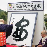 Seihan Mori, the chief priest of Kiyomizu Temple in Kyoto, writes the kanji an, meaning safety or peace, on a large sheet of washi paper Tuesday after the character was selected as the kanji best symbolizing the national mood in 2015. | KYODO