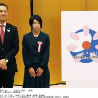 During a ceremony at the prime minister\'s office Monday, Shiho Utsumiya, 18, stands next to her logo design for next year\'s Group of Seven summit in the Ise-Shima area in Mie Prefecture. | KYODO