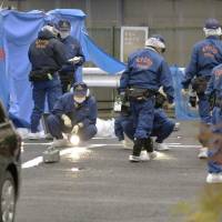 Kyoto Prefectural Police investigators are seen searching a parking lot in Kyoto on Dec. 19, 2013, after Takayuki Ohigashi, president of Ohsho Food Services, was found shot to death there. | KYODO