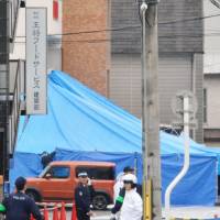 Police officials are seen on Dec. 19, 2013, around the headquarters of Ohsho Food Services in Kyoto. The company\'s president Takayuki Ohigashi was found shot to death at a parking lot near the headquarters. | KYODO