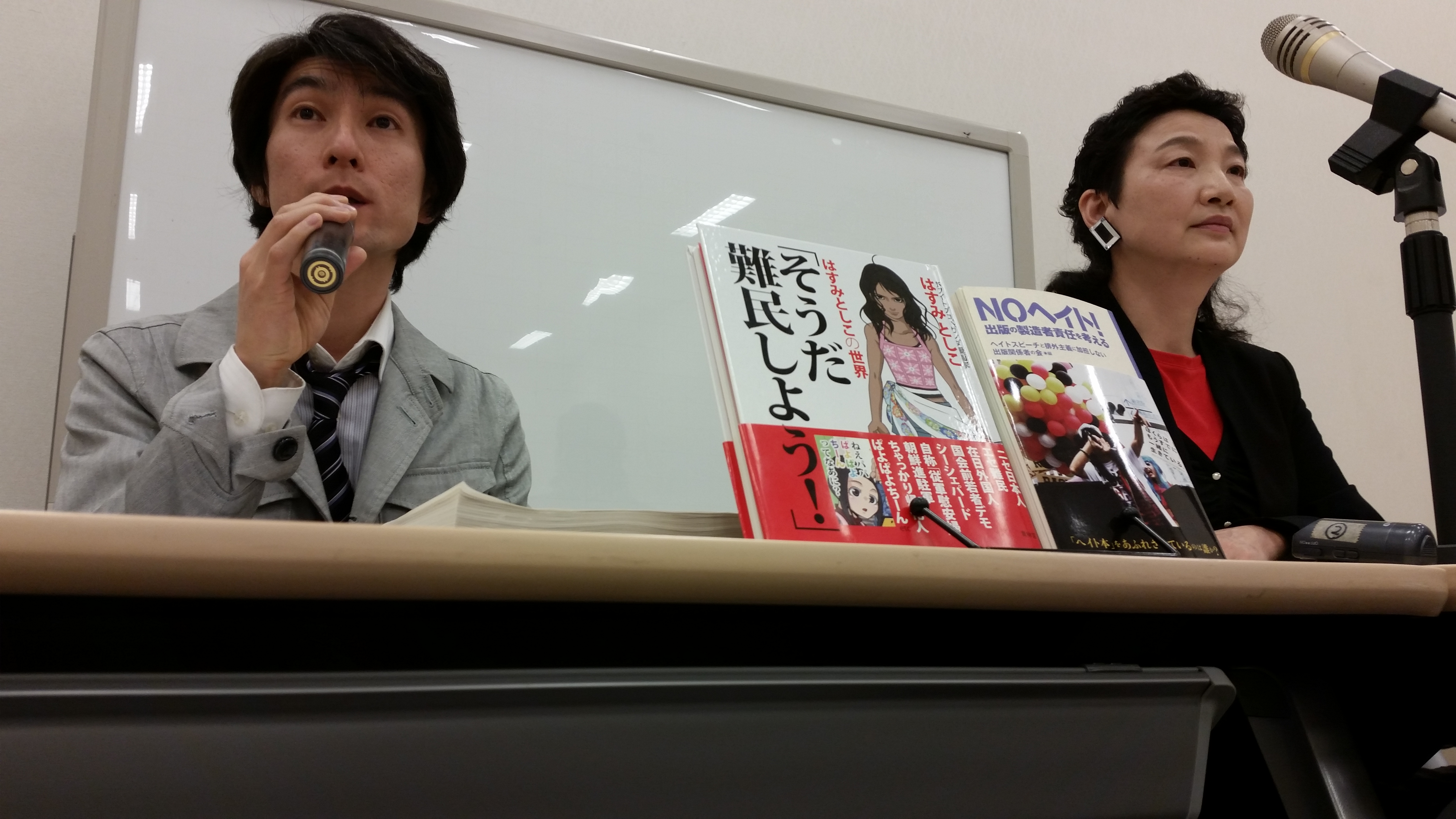 Anti-racism campaigners Yu Iwashita (left) and Shin Sugok protest the release of a book compiling what they called 'racist' cartoons drawn by artist Toshiko Hasumi during a news conference in Tokyo on Monday. | TOMOHIRO OSAKI