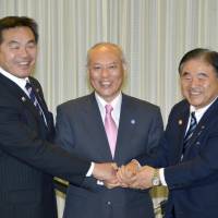 Sports and education minister Hiroshi Hase (left), Tokyo Gov. Yoichi Masuzoe (center) and Olympics minister Toshiaki Endo demonstrate their solidarity for the cameras Tuesday after striking a cost-sharing deal on the main stadium for the 2020 Olympics. | KYODO