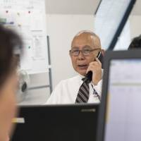 Kunitaka Nakajima, 72, fields a call at MyStar60, an employment agency for seniors looking for work, in Tokyo on Nov. 26. | ROB GILHOOLY