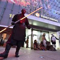 Fans dressed as various \"Star Wars\" characters pose in front of a Toho Cinemas in Roppongi to celebrate for the opening of \"Star Wars: The Force Awakens\" on Friday. | AFP-JIJI