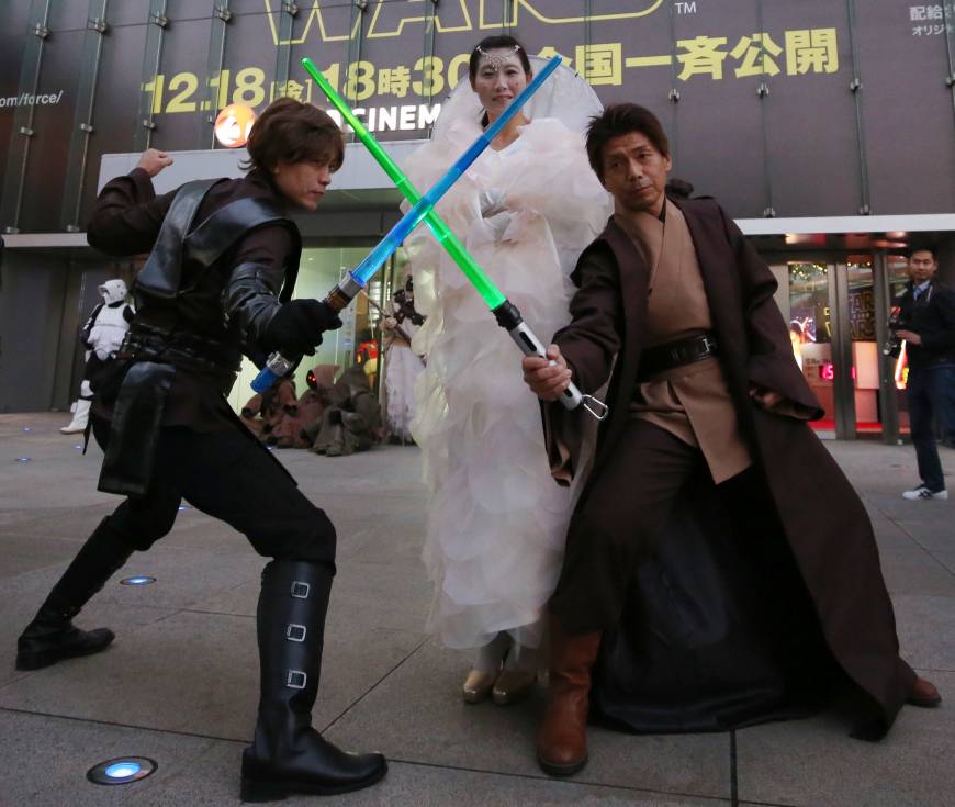 Men wielding lightsabers strike a pose with a woman dressed as Padme Amidala in front of Toho Cinemas' Roppongi Hills theater in Tokyo's Minato Ward on Friday ahead of the premiere of The Force is strong with Japanese ‘Star Wars’ fans