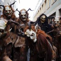 Men dressed as Krampus prepare to walk around the Christmas market in Munich on Sunday. Young single men clothed in animal skins and masks parade about the city ringing large cow-bells and making scary noises. They supposedly follow St. Nicholas from house to house every December to bring luck to the good and punish the idle. | REUTERS