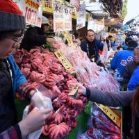 A customer buys octopus Tuesday at the Ameyoko shopping district in Taito Ward, Tokyo, as part of the annual rush for groceries for New Year\'s meals. | SATOKO KAWASAKI