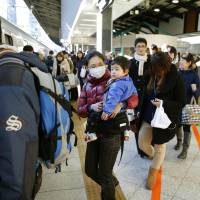 People board a bullet train at JR Tokyo Station on Tuesday on their way to spend the New Year\'s holidays in their hometowns. Many domestic flights and long-distance trains are fully booked as the holiday period goes into full swing. | KYODO