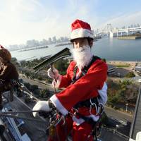 Suspended by ropes 31 meters above ground, window washers dressed as Santa Claus and his reindeer clean the Decks Tokyo Beach complex in the Odaiba waterfront area in Tokyo\'s Minato Ward on Thursday. | SATOKO KAWASAKI