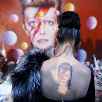 A woman with a Ziggy Stardust tattoo gets emotional as she visits the same mural. | REUTERS