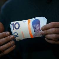 A man holds a 10 Brixton Pounds note, which is decorated with an image of David Bowie. | REUTERS