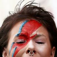 The same woman cries as she visits a mural of David Bowie in Brixton on Monday. | REUTERS