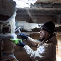 Mawson\'s Huts Foundation chief conservator Ian Godfrey chips ice from shelves in Douglas Mawson\'s bedroom in Mawson\'s Huts at Cape Denison in Antarctica last month. | REUTERS