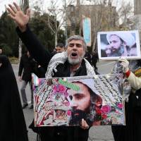An Iranian worshipper holds a poster showing Sheikh Nimr al-Nimr, a prominent opposition Saudi Shiite cleric who was executed by Saudi Arabia, as he chants slogans while attending an anti-Saudi protest rally after Friday prayers in Tehran. | AP