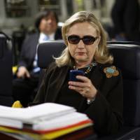 Then-Secretary of State Hillary Clinton checks her Blackberry from a desk inside a C-17 military plane upon her departure from Malta, in the Mediterranean Sea, for Tripoli in October 2011. The Obama administration confirmed Friday for the first time that Clinton\'s unsecured home server contained some closely guarded secrets, including material requiring one of the highest levels of classification. | AP