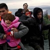 Refugees and migrants arrive on an inflatable raft on the Greek island of Lesbos on Saturday. | REUTERS