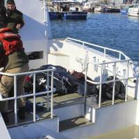 Turkish coast guardsmen arrive with bodies of migrants who drowned as they were trying to reach Greece, at a port near Izmir, Turkey, Thursday. | IHA VIA AP