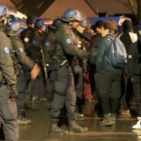 French gendarmes control migrants near the Grande-Synthe jungle of makeshift shelters, near Dunkirk, France, after three migrants were injured, one by gunshots, in what a charity worker said appeared to be a fight between rival bands of smugglers Tuesday. | REUTERS