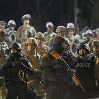 Police and Missouri National Guardsmen face protesters in front of the Ferguson Police Department on Nov. 28, 2014. | AP