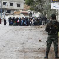 Syrian Army soldiers monitor residents who said they have received permission from the Syrian government to leave the besieged town as they wait with their belongings after an aid convoy entered Madaya, Syria, Thursday. Aid was sent on Thursday to the Syrian town blockaded by pro-government forces and two villages besieged by rebels for the second time this week, and a U.N. official said he hoped to make more deliveries to areas where people are starving. | REUTERS