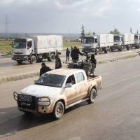 A vehicle belonging to Jaish al-Fatah (Army of Conquest) drives along convoys from the Syrian Arab Red Crescent carrying aid for the besieged towns of Fuaa and Kafraya, in Syria\'s northwest Idlib province, on Thursday. A spokesman for the International Committee of the Red Cross said that a convoy of 44 aid trucks was travelling from Damascus to Madaya, while a separate convoy of 17 trucks left the capital for Fuaa and Kafraya, two towns in Syria\'s northwest encircled by rebels. | AFP-JIJI
