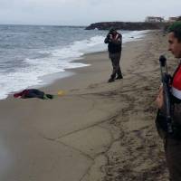 Turkish solders take photos of the body of a migrant washed up ashore in Izmir\'s Dikili district on Tuesday. The bodies of 17 migrants were found washed up on Turkey\'s western coast after boats taking them across the Aegean Sea toward EU member Greece sank in bad weather, the Dogan news agency reported. | TAYLAN YILDIRIM/ DOGAN NEWS AGENCY / AFP-JIJI