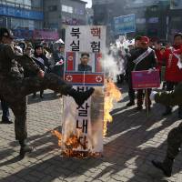 A member of a South Korean conservative group kicks a burning banner bearing the image of North Korean leader Kim Jong Un and the country\'s flag during a rally denouncing Pyongyang in Paju, South Korea, on Monday. | AP