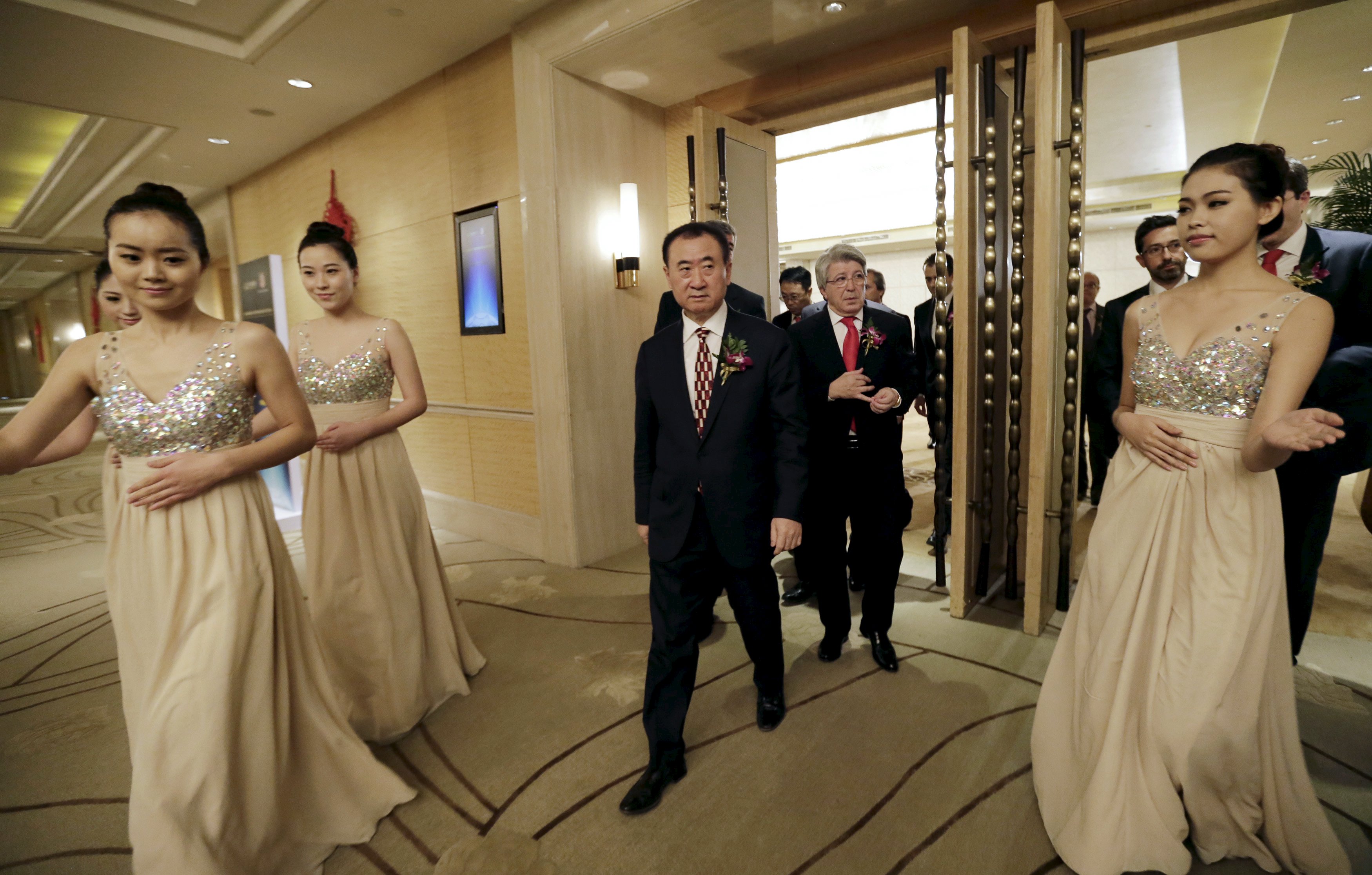 Wang Jianlin (center front), chairman of Dalian Wanda Group, and Atletico Madrid's President Enrique Cerezo arrive for a signing ceremony in Beijing on Jan. 21, 2015, when Wanda bought a 20 percent stake in the Spanish soccer club. | REUTERS