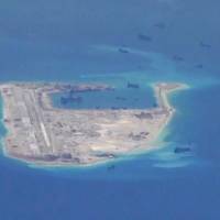 Chinese dredging vessels are purportedly seen in the waters around Fiery Cross Reef in the disputed Spratly Islands in the South China Sea in this still image from video taken by a U.S. Navy P-8A Poseidon surveillance aircraft in May. | U.S. NAVY / REUTERS
