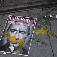 A picture of Russian President Vladimir Putin is splattered with eggs during an October protest in Istanbul. The slogan, in Turkish and Russian, reads \"Murderer Putin\" | AP