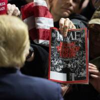 A man holds up a copy of Time magazine as Republican presidential candidate Donald Trump greets members of the audience after speaking at a rally at Muscatine High School in Muscatine, Iowa, Sunday. | AP