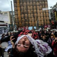 A group of street artists hold a woman during a demonstration Sunday on Istiklal avenue in Istanbul. Turkish security forces killed 18 militants from the Kurdistan Workers\' Party (PKK) as they battled the rebels in curfew-hit towns in the country\'s troubled southeast, the army said Saturday. | AFP-JIJI