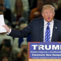 U.S. Republican presidential candidate Donald Trump holds up his notes of a recent poll at a campaign rally in Claremont, New Hampshire, Tuesday. | REUTERS