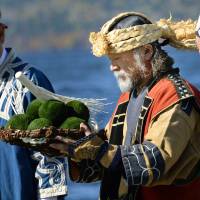 Masao Nishida prays in an Ainu ritual at Hokkaido\'s Lake Akan in October. Marimo (moss balls) are returned to the lake to thank the gods for a rich harvest. | KYODO