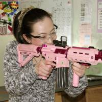 A woman aims for a target with an airsoft gun at Shooting Cafe Rock On in the city of Fukui on Dec. 16. | KYODO