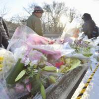 People place flowers Tuesday at a spot along National Route 18 in Karuizawa, Nagano Prefecture, where a ski tour bus carrying several university students crashed last week, killing 15 people. | Kyodo
