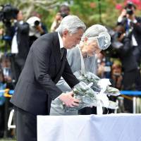 Emperor Akihito and Empress Michiko lay flowers during a visit to the Japanese Memorial Garden in Caliraya, Laguna province, in the Philippines on Friday. | POOL/KYODO