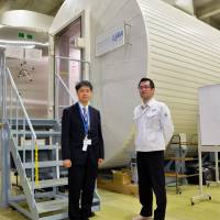 Japan Aerospace Exploration Agency officials show off a test facility in Tsukuba, Ibaraki Prefecture, on Wednesday. | KYODO