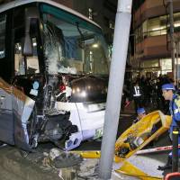 A damaged tour bus is seen after it crashed into a center divider and a traffic light near JR Kamata Station in Tokyo Wednesday night. | KYODO