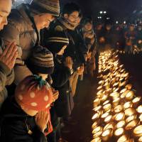 People pray for victims of the 1995 Great Hanshin Earthquake in front of bamboo lanterns in Higashi-Yuenchi Park in Kobe\'s Chuo Ward, Hyogo Prefecture, at around 5:46 a.m., the time the disaster struck. | KYODO