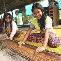 Young girls engage in weaving at the Community Factory operated by the Kamonohashi Project in northwestern Cambodia. | COURTESY OF KAMONOHASHI PROJECT