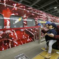 A father and son admire the Genbi Shinkansen, a specially decorated six-car bullet train, at JR Omiya Station in Saitama on Tuesday. | KYODO