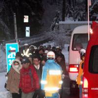 People evacuate a spa resort in Matsumoto, Nagano Prefecture, on Saturday after being stranded for about a day after trees knocked down by heavy snow blocked routes to the area. | KYODO